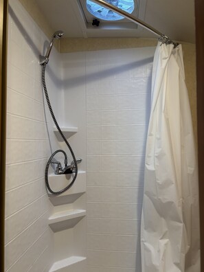 A shower area with a glass door, a showerhead, and a curtain.