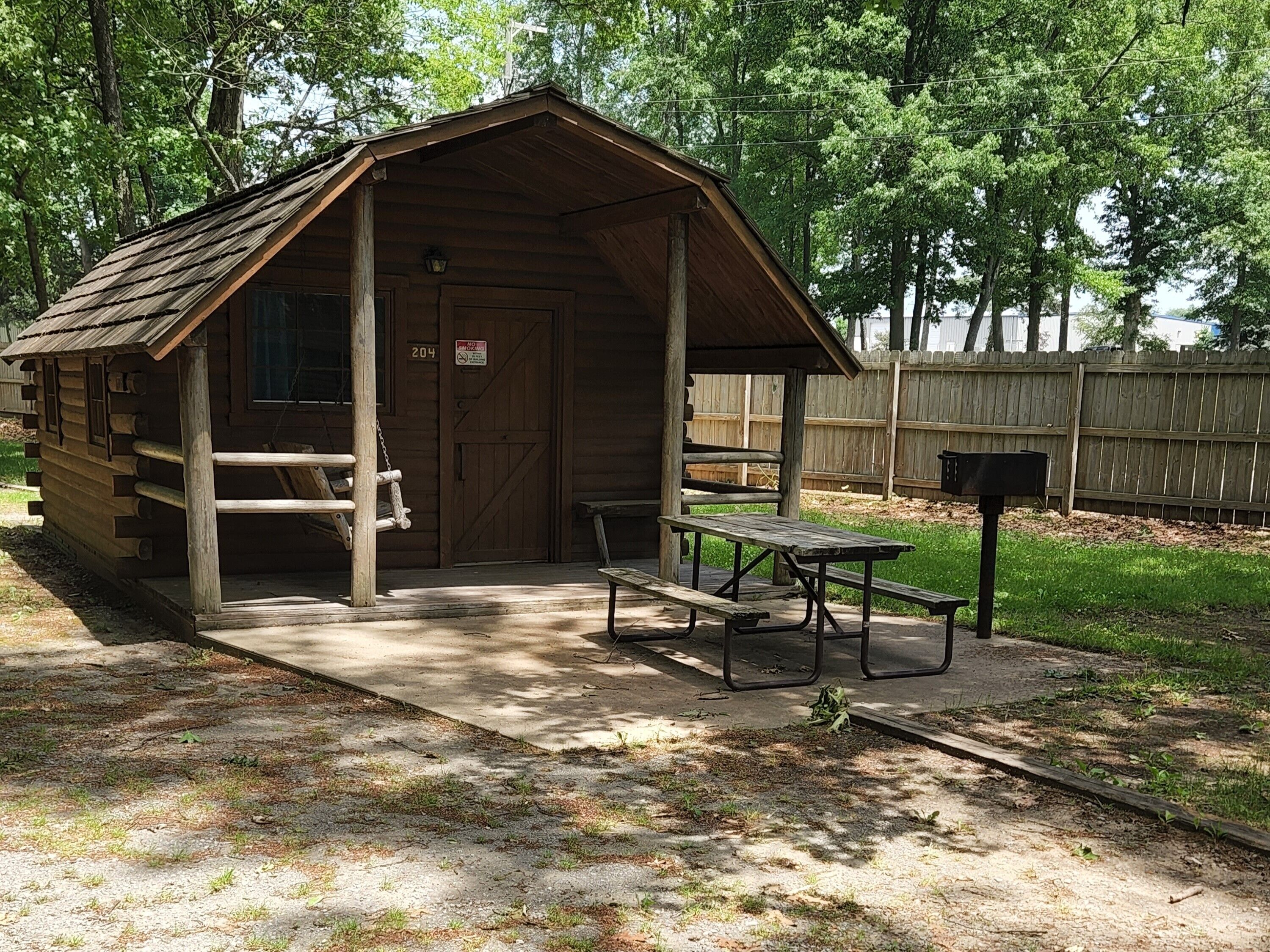 A wooden cabin with a porch, a picnic table, and a mailbox.