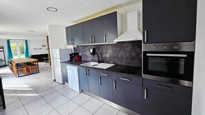 Una cocina moderna con armarios oscuros, horno integrado y cafetera.