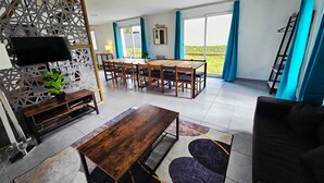 Un salón espacioso con una mesa de comedor, sofás y una televisión.