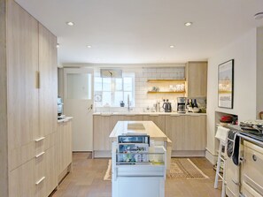Eine moderne Küche mit Holzausstattung, einer zentralen Kochinsel und einem eingebauten Ofen.