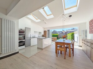 Una cocina moderna con tragaluces, un comedor con mesa y sillas, y vistas al exterior.