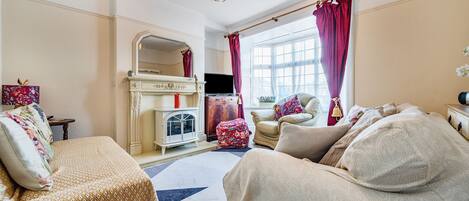 Una sala de estar con chimenea, televisor y sofá.