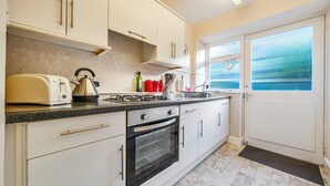 A kitchen with white cabinets, a toaster, a kettle, and a stove. - Ambleside Cottage with free private parking (Ambleside)