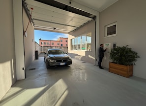 Un'auto parcheggiata in un garage, con una persona accanto a un dispositivo fissato al muro.