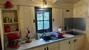 A compact kitchen with wooden cabinetry, a built-in sink, and a window providing natural light.