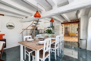 A dining area with a wooden table, white chairs, and red pendant lights.