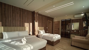 Een moderne hotelkamer met twee bedden, een zithoek en een kledingkast.