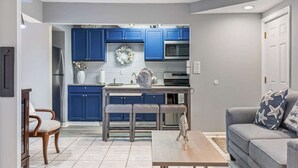 Una cocina moderna con armarios azules, una mesa de comedor con sillas y un sofá gris con almohadones estampados de estrellas.