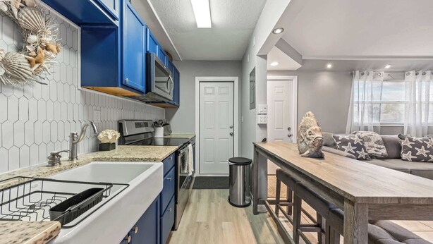 Una cocina moderna con armarios azules, un microondas y un lavamanos.