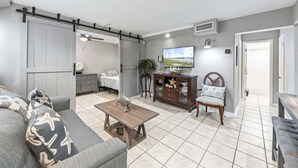 Una sala de estar con un sofá, una mesa de centro, un televisor, un mueble y una silla.