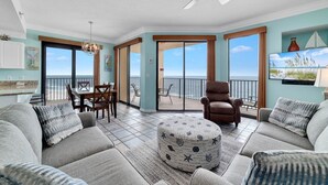 A spacious living area with a balcony, a dining set, and a comfortable seating arrangement. - Phoenix V 1117 3 Bedroom Condo (Orange Beach)