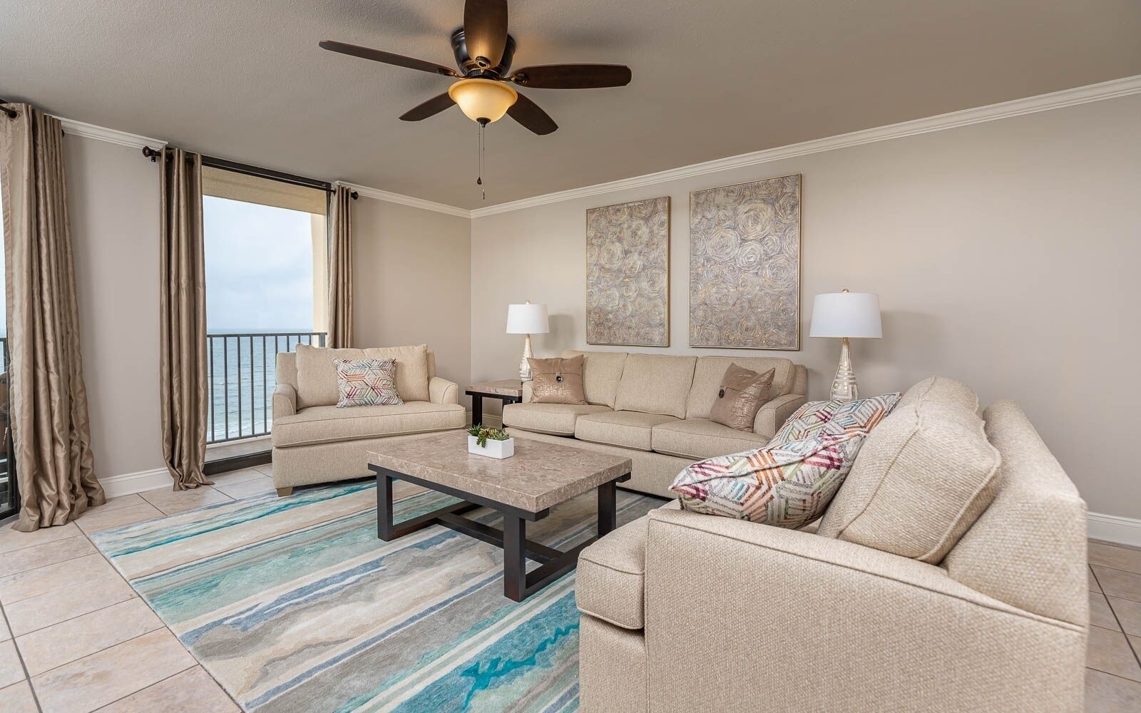 A living room with a sofa set, a coffee table, a ceiling fan, and artwork on the wall.