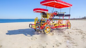 Ein Strandbuggy mit Verdeck, Rädern und Kennzeichen auf einem Sandstrand.