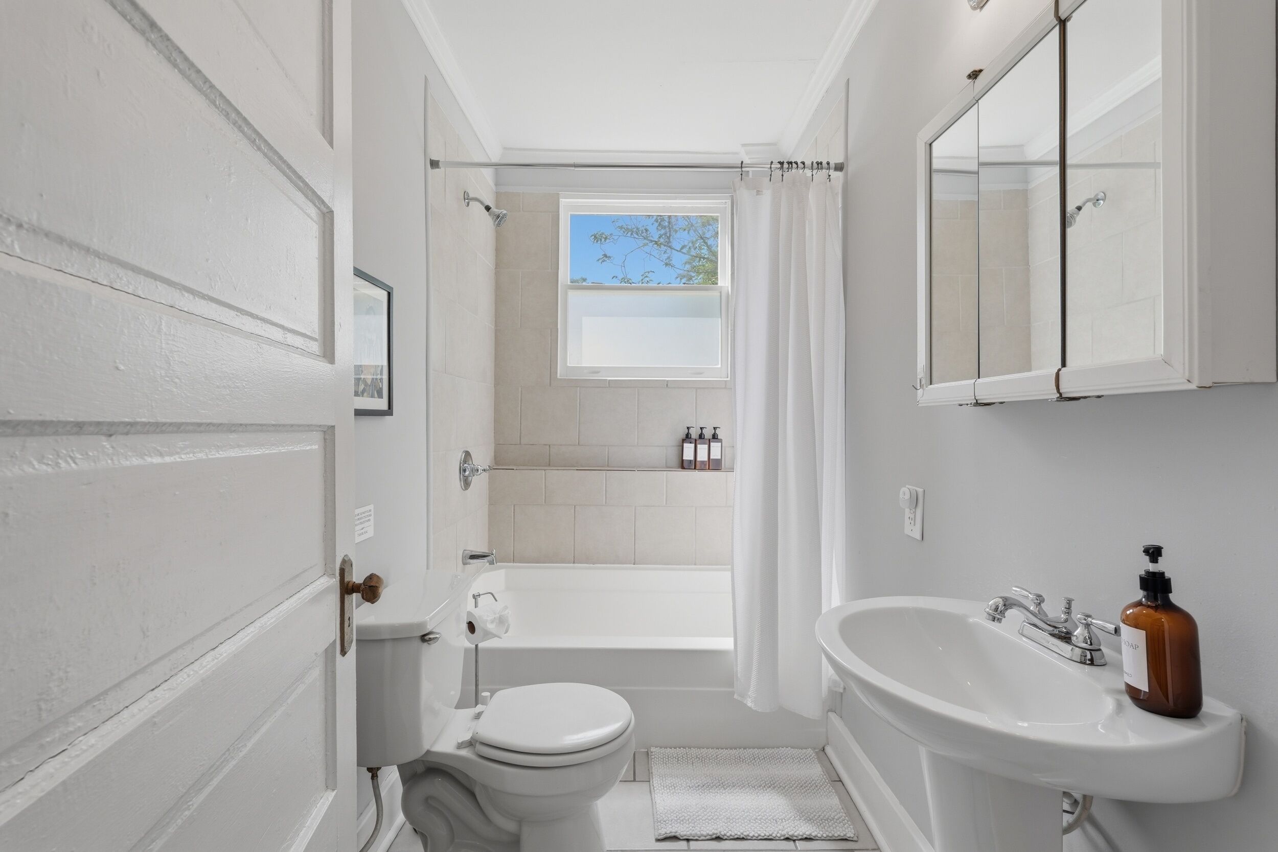 Un baño con inodoro, lavabo, bañera y ventana con vistas al exterior.