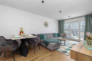 Un salon moderne comprenant un canapé, une table à manger, des chaises, un élément décoratif mural et une vue sur l’extérieur.