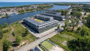Un complex modern d'edificis amb diverses plantes, una pista de tennis i un riu al fons.