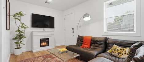A modern living room with a fireplace, leather sofa, and a flat-screen TV.
