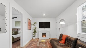 Un salon moderne avec une cheminée, un canapé en cuir et un téléviseur à écran plat.