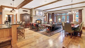 A spacious living room with a fireplace, wooden beams, and a dining area with chairs. - 3BR Condo In Bachelor Gulch, Ski In/out (Avon)