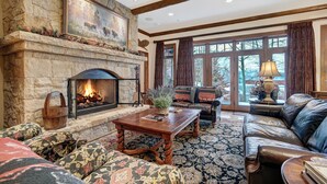 A stone fireplace, leather sofa, and a large window with curtains. - 3BR Condo In Bachelor Gulch, Ski In/out (Avon)