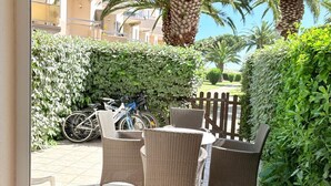 Un espacio al aire libre con techo, muebles de mimbre, una bicicleta y una palmera.