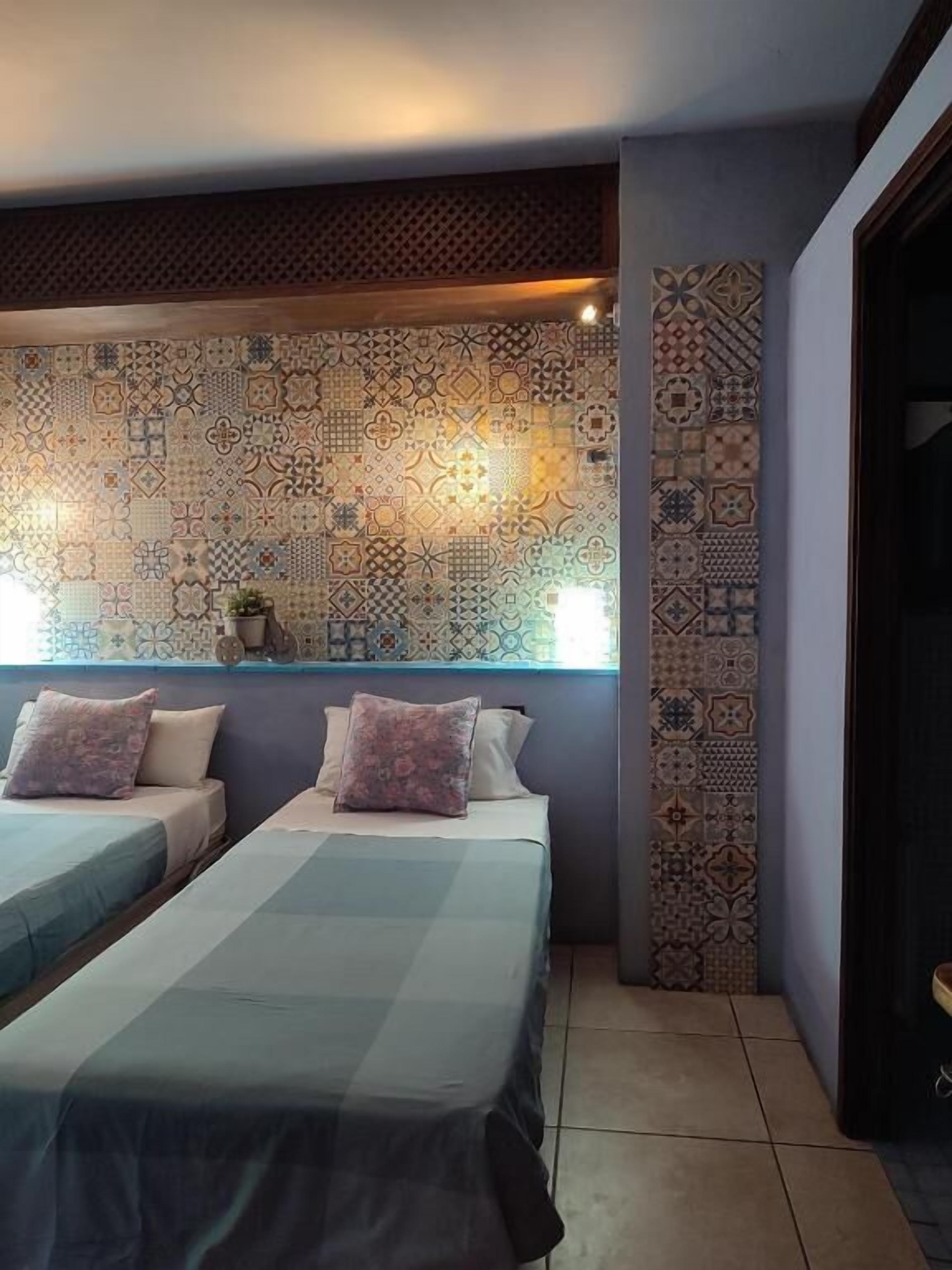 Habitació d'hotel amb dos llits, un mur decoratiu i una finestra.