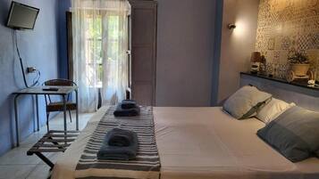 Un dormitorio con cama, escritorio, silla y televisor.