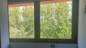A room with a window, a round table with a lamp, a chair, and a remote control. - Hotel Pasteral (La Cellera de Ter)