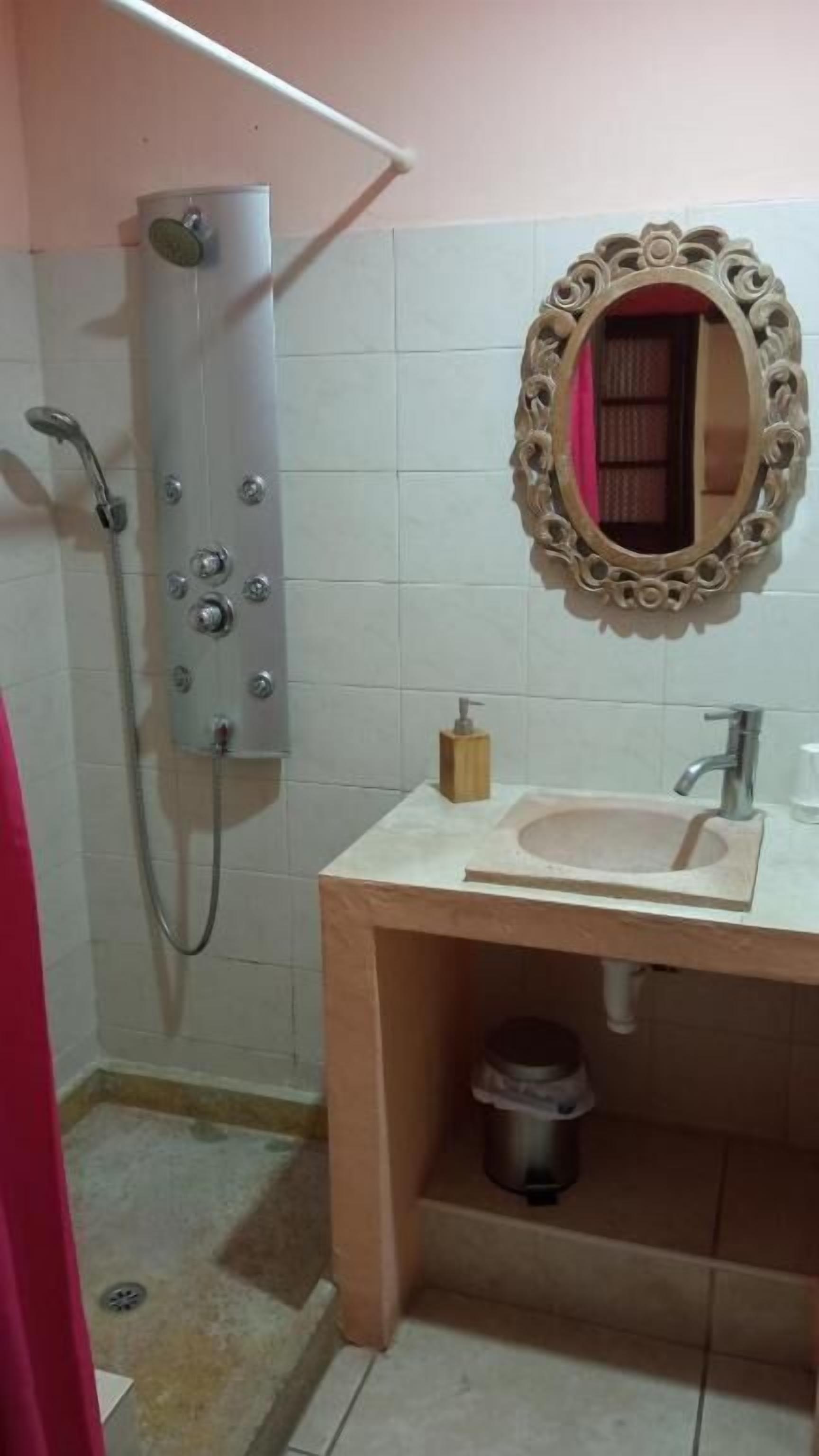 Ein Badezimmer mit Dusche, Waschbecken, Spiegel und Stauraumschrank.