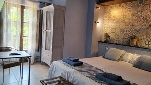 A bedroom with a bed, a table, a chair, a wardrobe, and a patterned wall. - Hotel Pasteral (La Cellera de Ter)