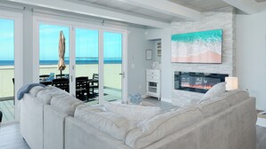 Un salon avec une cheminée, un canapé et une vue sur la plage.