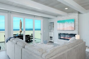 A living room with a fireplace, a sofa, and a view of the beach.