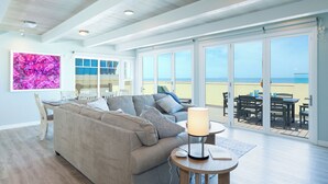 Un salon avec un canapé, une table et une lampe. Une grande fenêtre offre une vue sur la plage.