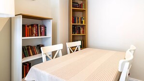 Ein Zimmer mit einem Tisch, zwei Stühlen und zwei Bücherregalen voller Bücher.