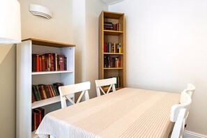 Ein Zimmer mit einem Tisch, zwei Stühlen und zwei Bücherregalen voller Bücher.