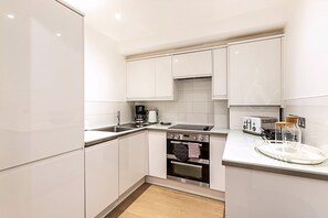 Eine moderne Küche mit weißen Schränken, einem Einbauofen, einer Kaffeemaschine und einem Toaster.