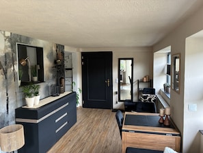 A modern living room with a black sofa, a wooden coffee table, and a black cabinet with plants. - Apartment 'Fewo Abendruh' with Private Terrace and Wi-Fi (Elzach)