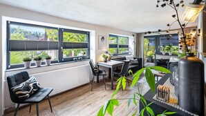 A modern interior with a dining area, seating, and large windows. - Apartment 'Fewo Abendruh' with Private Terrace and Wi-Fi (Elzach)