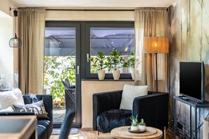 Een woonkamer met een bank, een salontafel, een televisie en een raam met gordijnen.