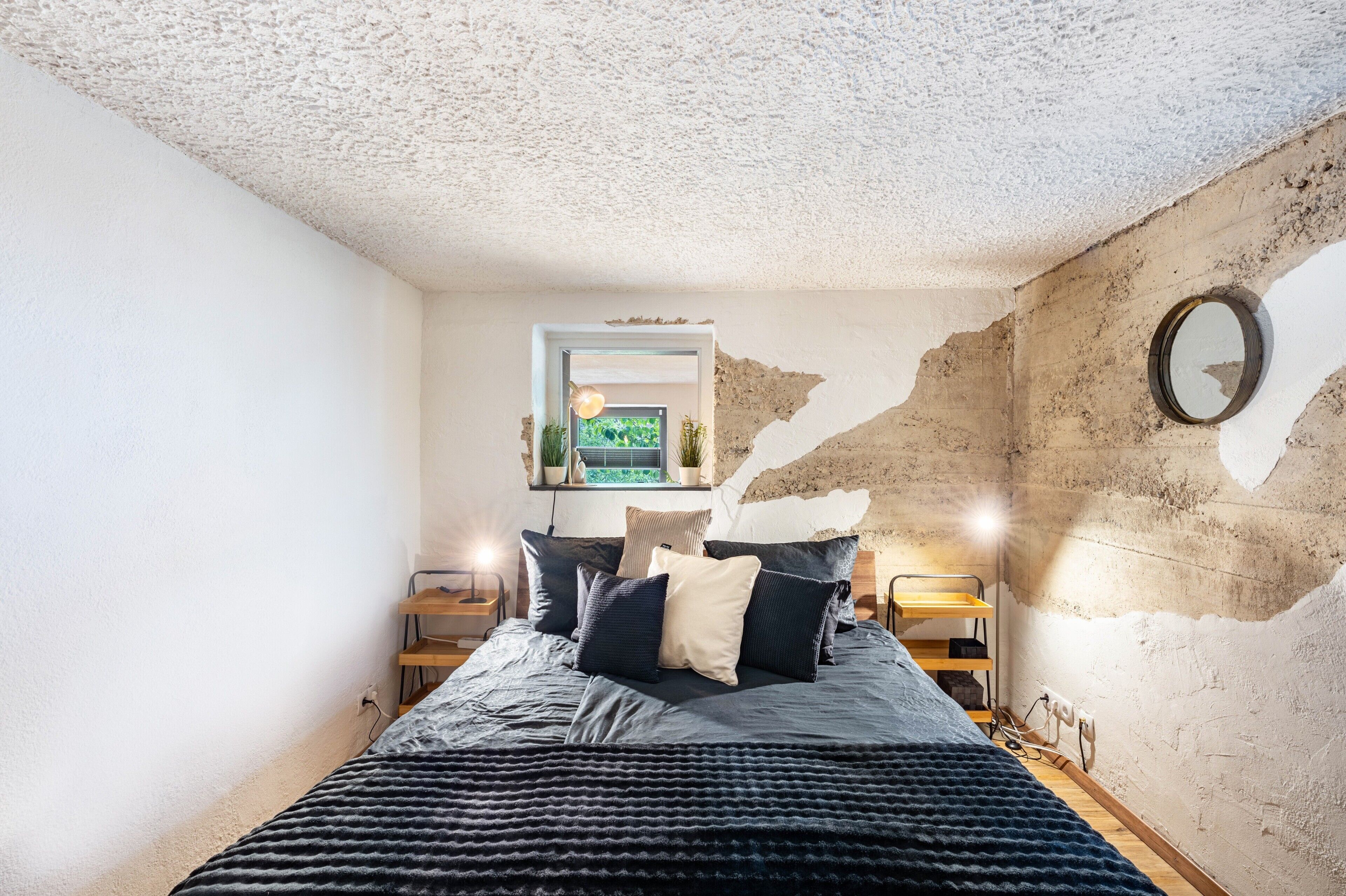 Een slaapkamer met een bed, nachtkastjes, een spiegel en een raam met uitzicht.
