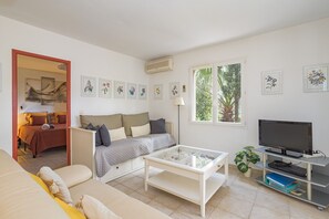 A modern living room with a sofa, a coffee table, a TV on a stand, and framed artwork on the walls. - Charming Apartment with Panoramic Sea Views in Collioure (Collioure)