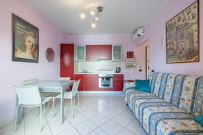 Een kleine leefruimte met een kitchenette, eethoek en een bank.
