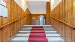 Una escalera con paneles de madera y peldaños de mármol, que conduce a una puerta en la parte superior.