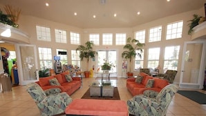 A spacious lobby with two sofas, a coffee table, and a bench. There are potted plants and a vending machine.