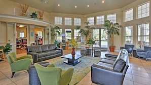 A spacious lobby with leather sofas, green armchairs, and a central coffee table.