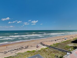 A beach with a wooden boardwalk, sandy shore, and ocean waves. - Indies House 502 | Stunning Getaway (Ormond Beach)