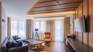 A modern living room with a sofa, armchair, coffee table, and flat-screen TV.