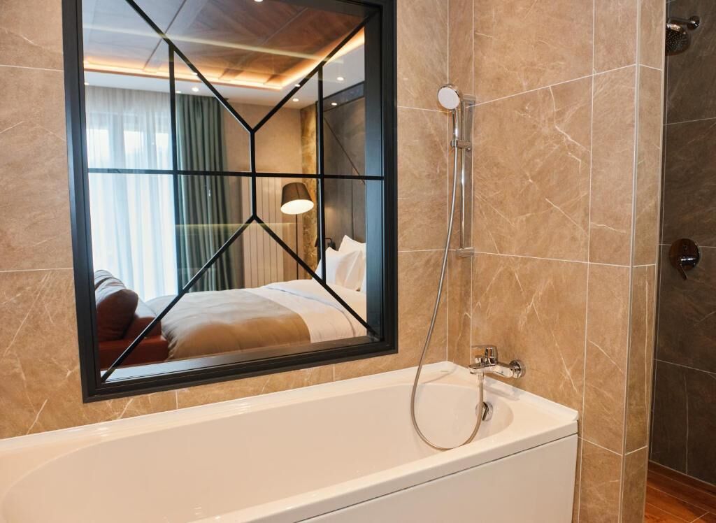 A modern bathroom with a large mirror, a bathtub, and a shower.