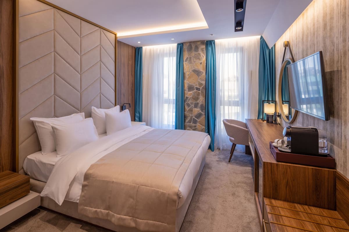 Une chambre d’hôtel comprenant un lit, un bureau, une chaise, un téléviseur et un mur décoratif en pierre.